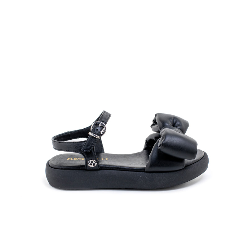 Sandalo in pelle tubolare total black, con morbido maxifiocco ton sur ton. Fondo platform e cinturino con fibbia. Artigianale e Made in Italy.