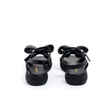 Sandalo in pelle tubolare total black, con morbido maxifiocco ton sur ton. Fondo platform e cinturino con fibbia. Artigianale e Made in Italy.