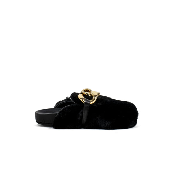 Slipper in pelliccia nera con catena d’oro sul fronte.